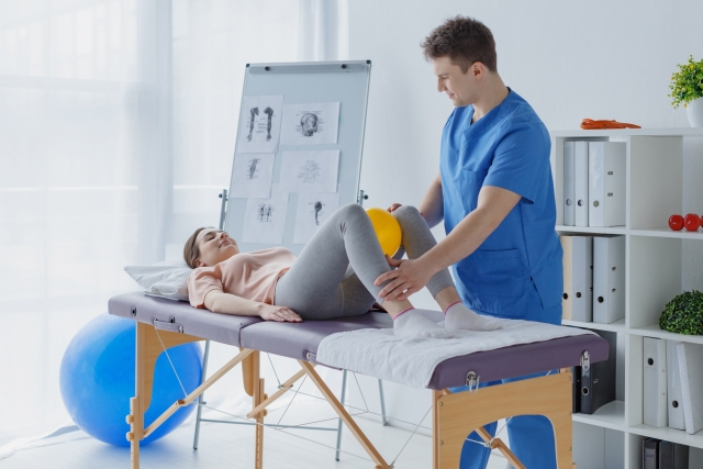 ベッドでリハビリを受ける女性と医学療法士